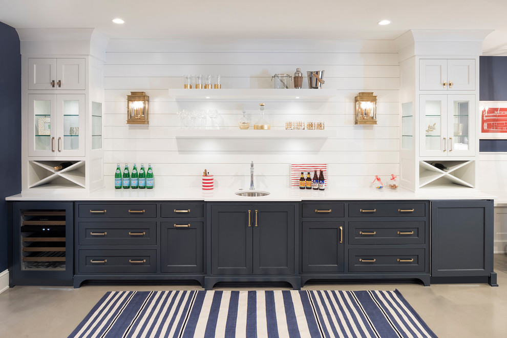 This is an example of a beach style single-wall wet bar in Minneapolis with an undermount sink, shaker cabinets, blue cabinets, white splashback, timber splashback, grey floor, white benchtop and concrete floors.