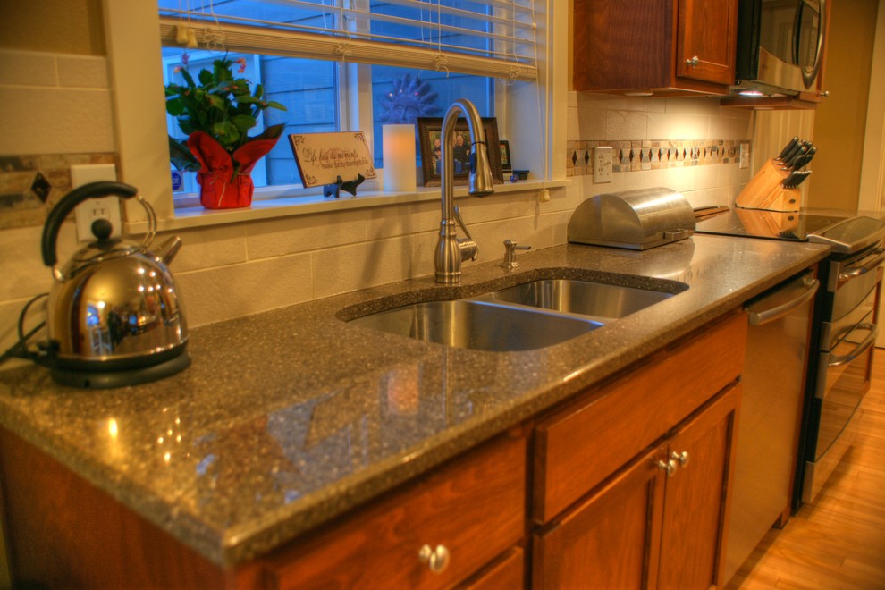 Example of a mid-sized transitional galley light wood floor eat-in kitchen design with an undermount sink, raised-panel cabinets, brown cabinets, quartz countertops, white backsplash, porcelain backsplash, stainless steel appliances, yellow walls and a peninsula