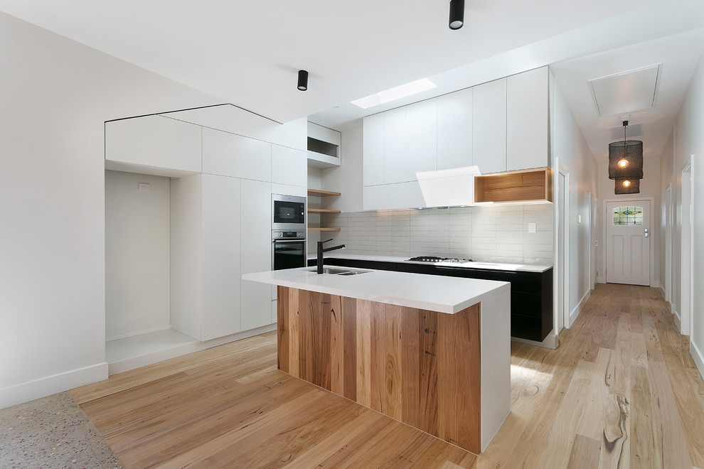 Design ideas for a modern kitchen in Melbourne with white splashback, stainless steel appliances and with island.