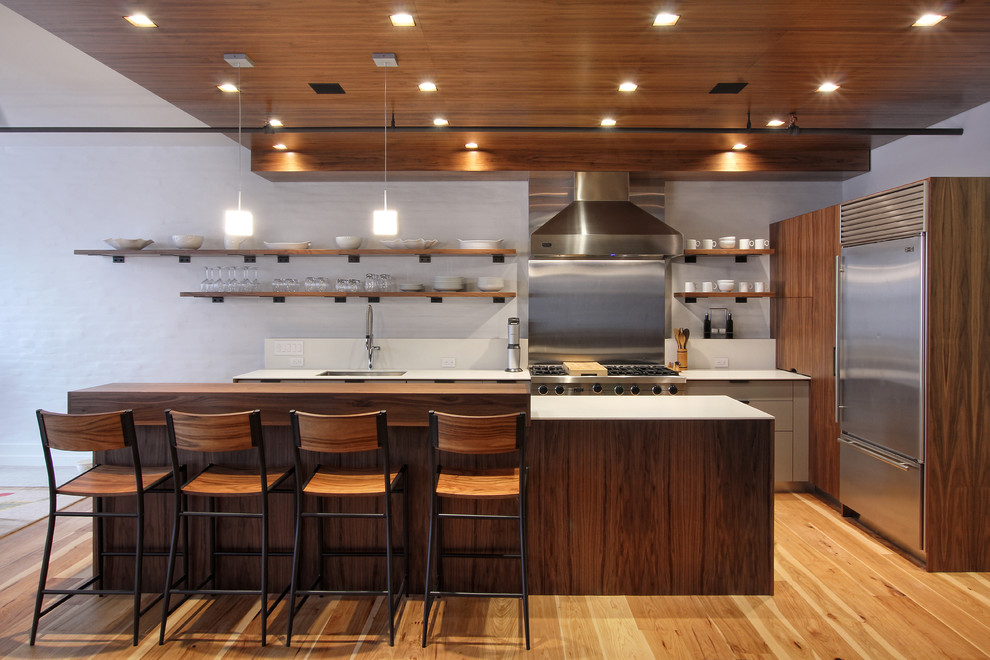 This is an example of a mid-sized contemporary l-shaped kitchen in New York with an undermount sink, flat-panel cabinets, medium wood cabinets, metallic splashback, stainless steel appliances, medium hardwood floors and with island.