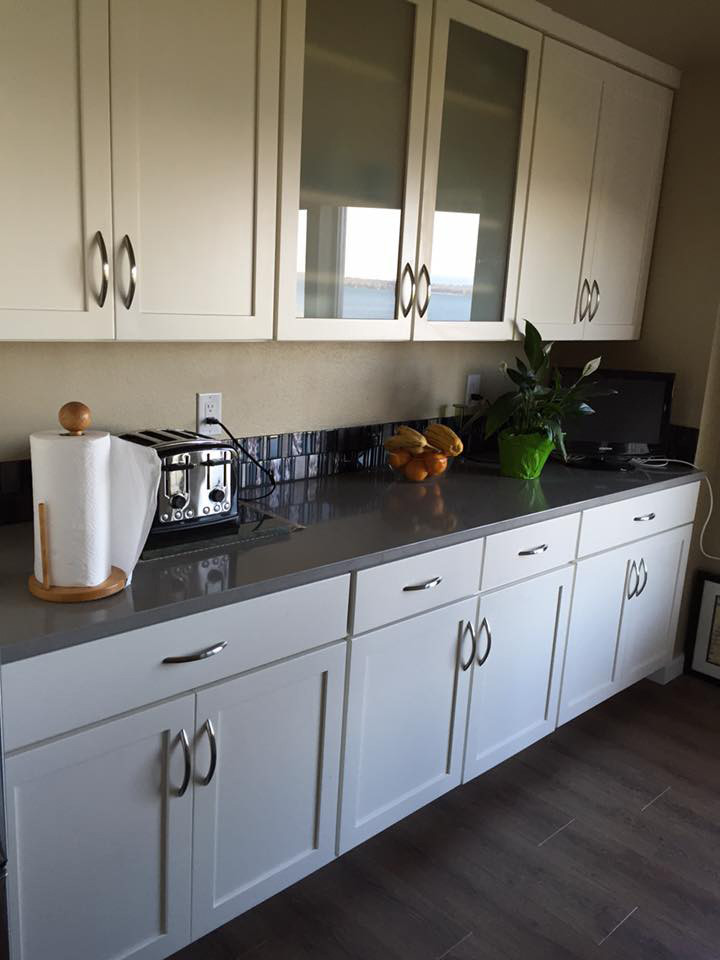Inspiration for a mid-sized transitional l-shaped open concept kitchen remodel in Seattle with an undermount sink, shaker cabinets, white cabinets, quartzite countertops, metallic backsplash, glass tile backsplash, stainless steel appliances and an island