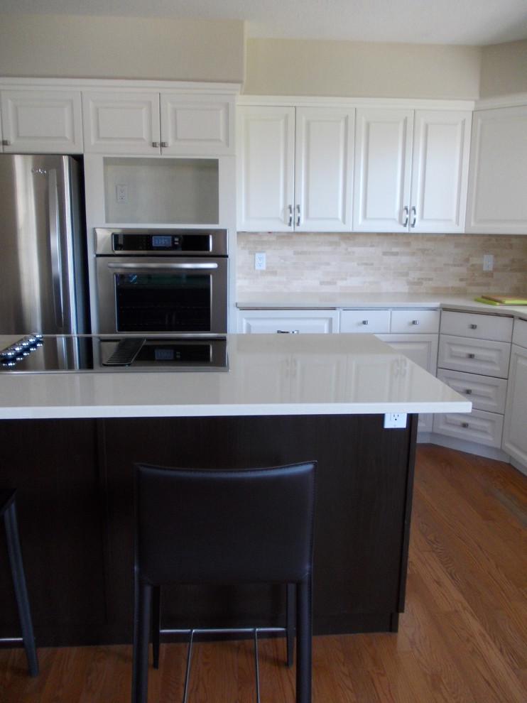Transitional l-shaped eat-in kitchen photo in Vancouver with raised-panel cabinets, white cabinets, solid surface countertops, stone tile backsplash, stainless steel appliances and an island