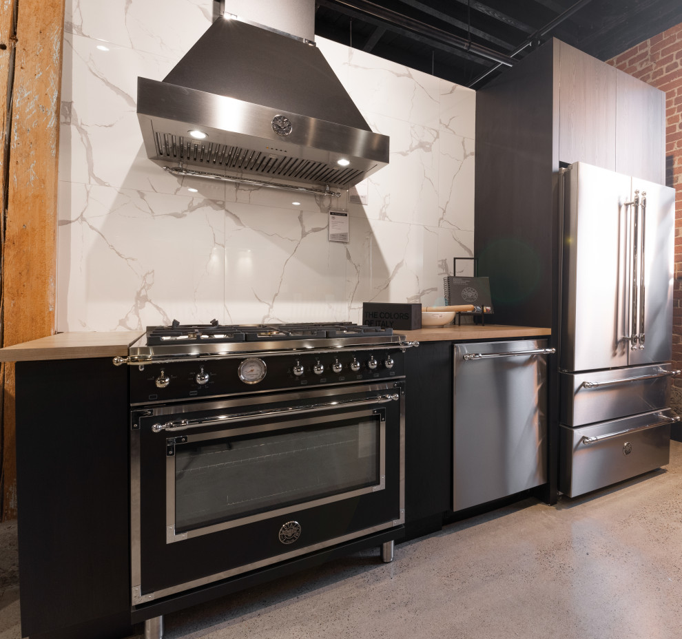Immagine di una cucina moderna con ante nere, top in legno, paraspruzzi bianco, paraspruzzi in marmo, elettrodomestici in acciaio inossidabile e top marrone