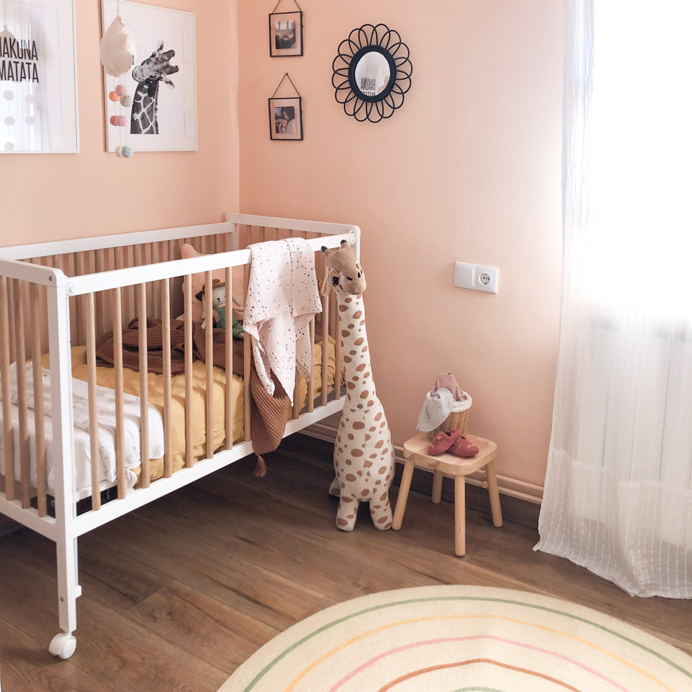 Esempio di una piccola cameretta per bambini da 1 a 3 anni nordica con pareti rosa e parquet scuro