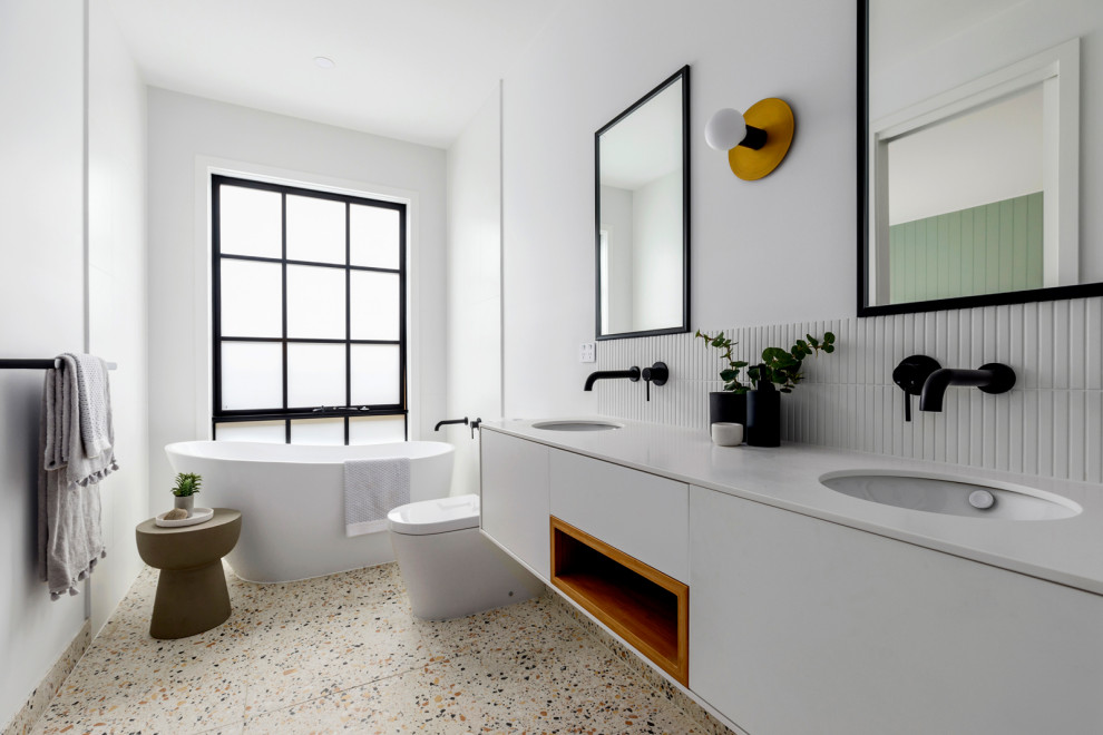 Inspiration for a contemporary master bathroom in Melbourne with flat-panel cabinets, white cabinets, a freestanding tub, white tile, white walls, terrazzo floors, an undermount sink, multi-coloured floor, white benchtops, a double vanity and a floating vanity.