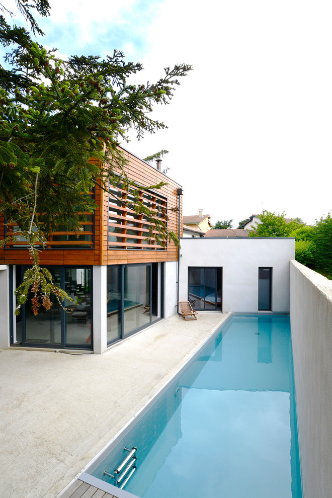 Photo of a mid-sized contemporary side yard rectangular lap pool in Lyon with concrete slab.