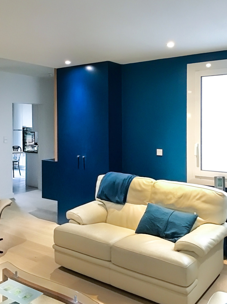 Cette photo montre un salon tendance de taille moyenne et ouvert avec un mur bleu, parquet clair et éclairage.