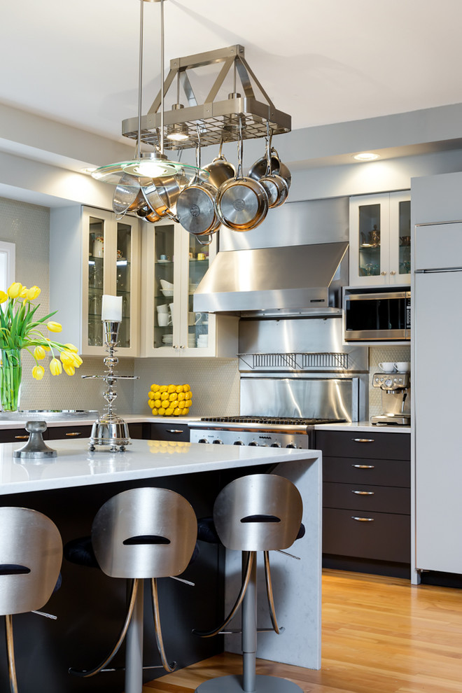 Example of a large transitional l-shaped light wood floor kitchen design with flat-panel cabinets, dark wood cabinets, gray backsplash, stainless steel appliances and an island