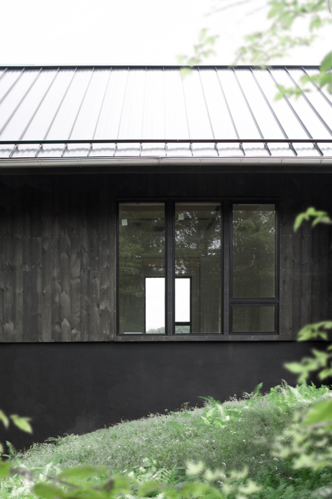 Inspiration pour une façade de maison noire nordique avec un toit noir.