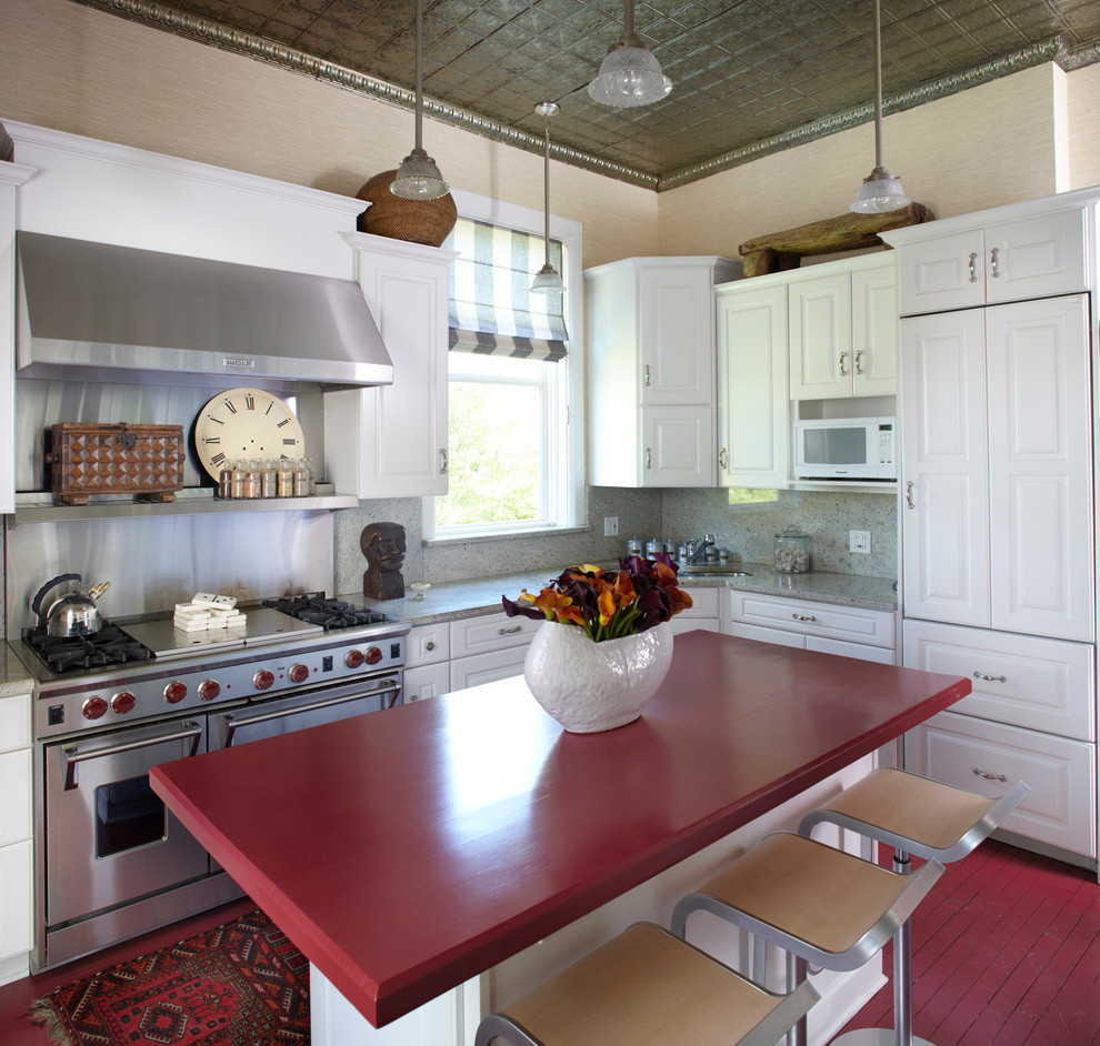 Traditional kitchen in Chicago with raised-panel cabinets, white cabinets, grey splashback, stainless steel appliances, painted wood floors, red floor and red benchtop.
