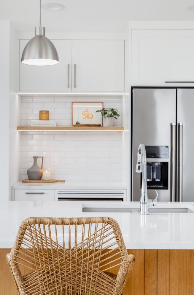 Example of a mid-sized transitional l-shaped light wood floor and beige floor eat-in kitchen design in Vancouver with an undermount sink, shaker cabinets, white cabinets, quartzite countertops, white backsplash, subway tile backsplash, stainless steel appliances, an island and white countertops