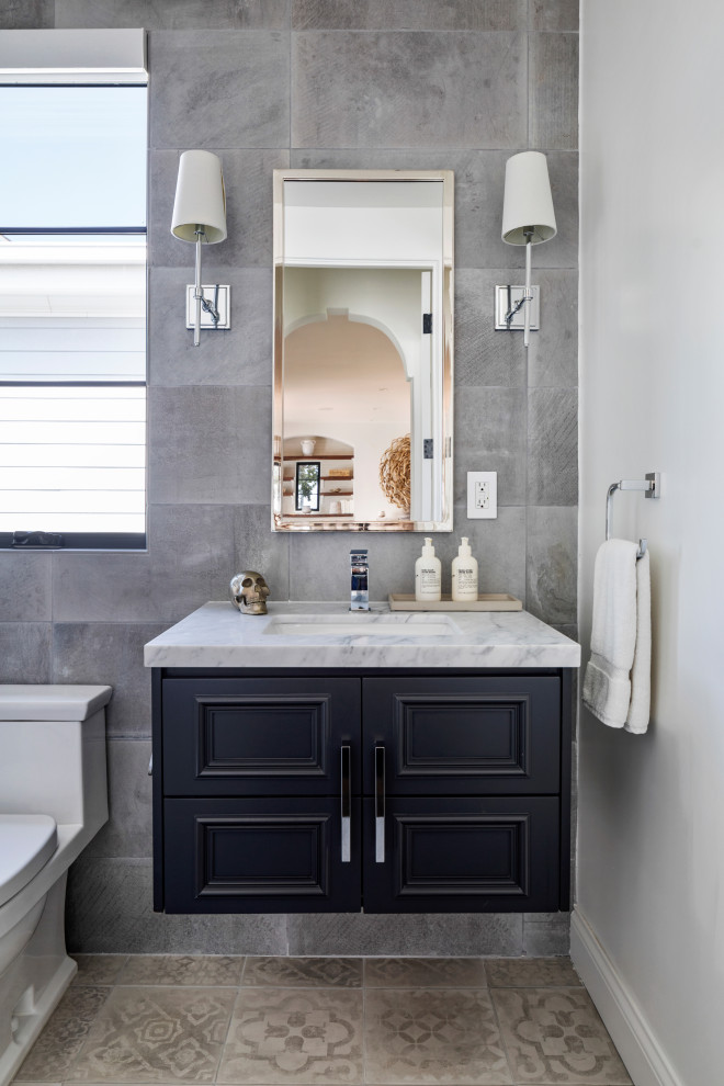 Mid-sized mediterranean 3/4 bathroom in Los Angeles with shaker cabinets, black cabinets, a one-piece toilet, gray tile, ceramic tile, porcelain floors, marble benchtops, black floor, multi-coloured benchtops, a single vanity and a floating vanity.