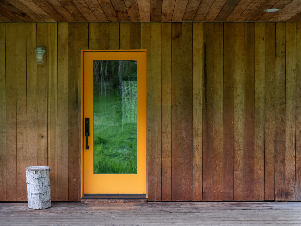 Cette photo montre une petite porte d'entrée montagne en bois avec une porte simple, une porte orange, un sol gris et un plafond en bois.