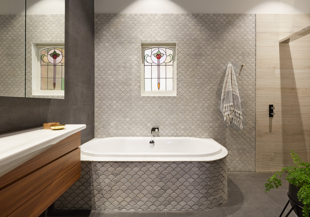 Design ideas for a mid-sized contemporary master bathroom in Melbourne with an open shower, gray tile, an open shower, medium wood cabinets, a corner tub, pebble tile, a vessel sink, laminate benchtops and flat-panel cabinets.