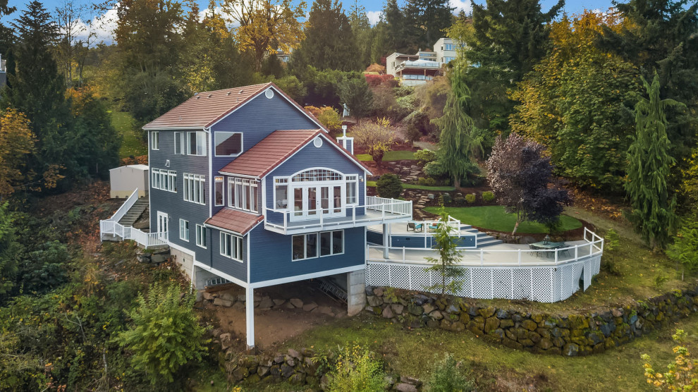На фото: большой, трехэтажный, деревянный, синий частный загородный дом в стиле неоклассика (современная классика) с двускатной крышей, черепичной крышей, красной крышей и отделкой планкеном с