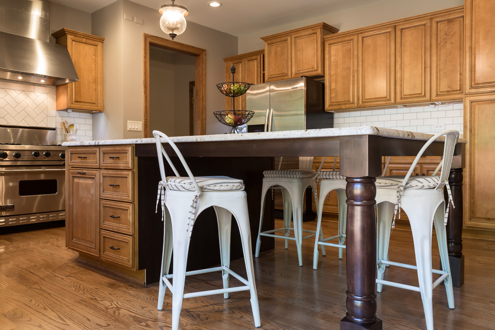 Example of a large transitional u-shaped medium tone wood floor kitchen design in Chicago with a single-bowl sink, raised-panel cabinets, medium tone wood cabinets, granite countertops, white backsplash, ceramic backsplash, stainless steel appliances and an island