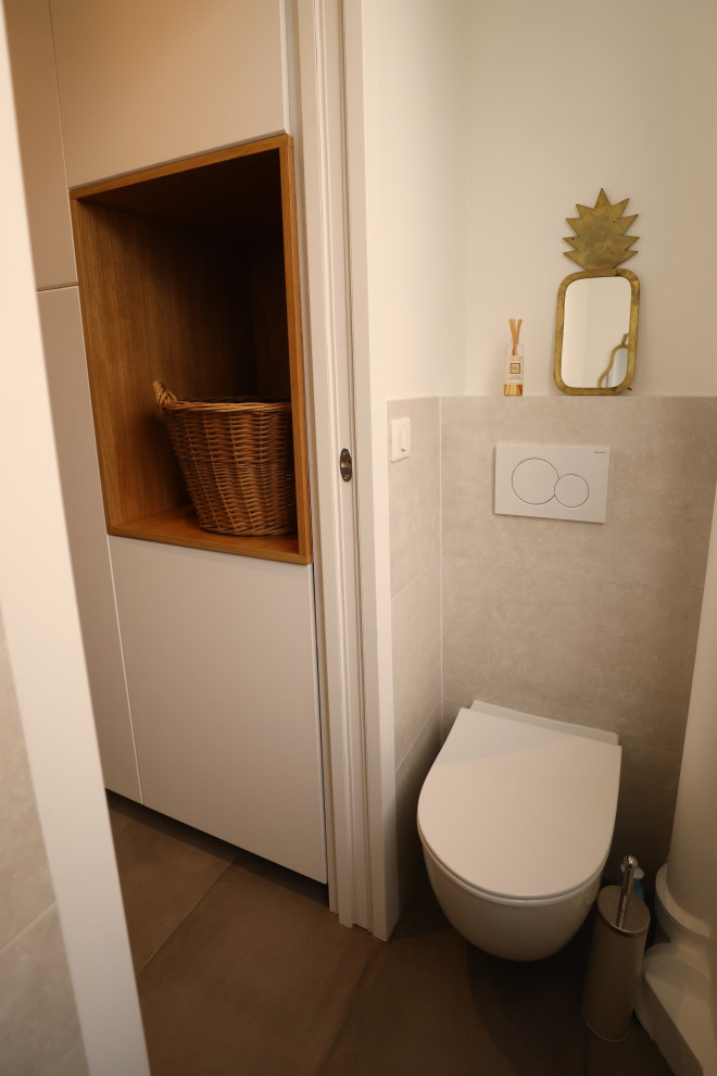Photo of a small contemporary cloakroom in Paris with beaded cabinets, white cabinets, a wall mounted toilet, grey tiles, white walls, ceramic flooring, a wall-mounted sink and a built in vanity unit.