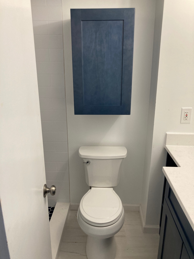 Design ideas for a small modern cloakroom in DC Metro with shaker cabinets, blue cabinets, a two-piece toilet, white tiles, porcelain tiles, white walls, porcelain flooring, a submerged sink, quartz worktops, white floors, white worktops and a built in vanity unit.