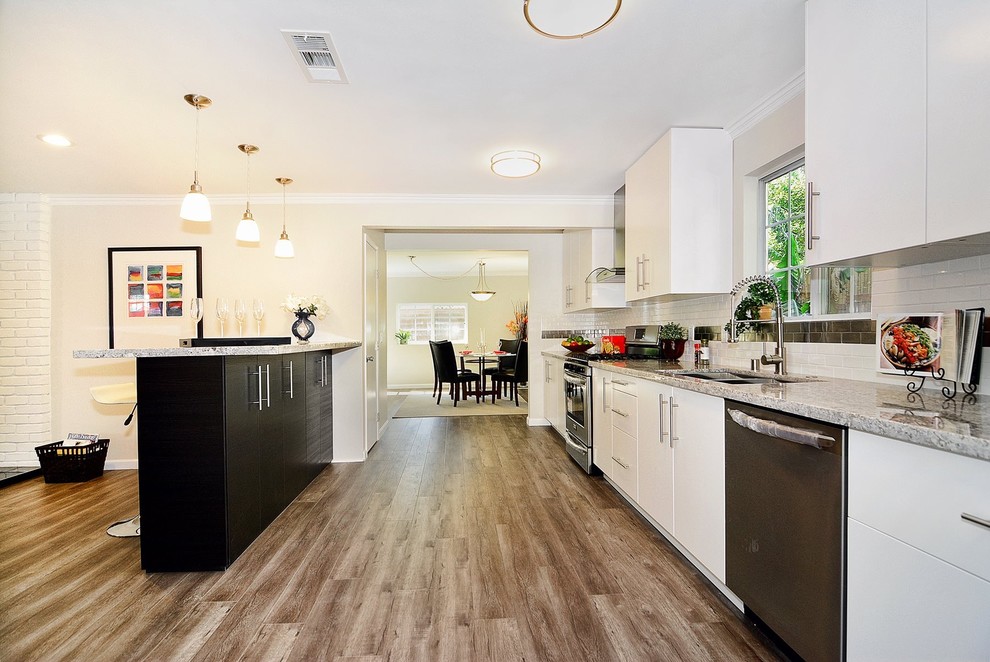 Example of a large transitional single-wall medium tone wood floor open concept kitchen design with a single-bowl sink, flat-panel cabinets, white cabinets, multicolored backsplash, stainless steel appliances and an island