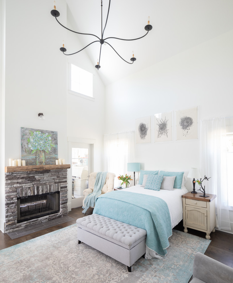 Design ideas for a mid-sized country master bedroom in Nashville with white walls, medium hardwood floors, a two-sided fireplace, a stone fireplace surround and brown floor.