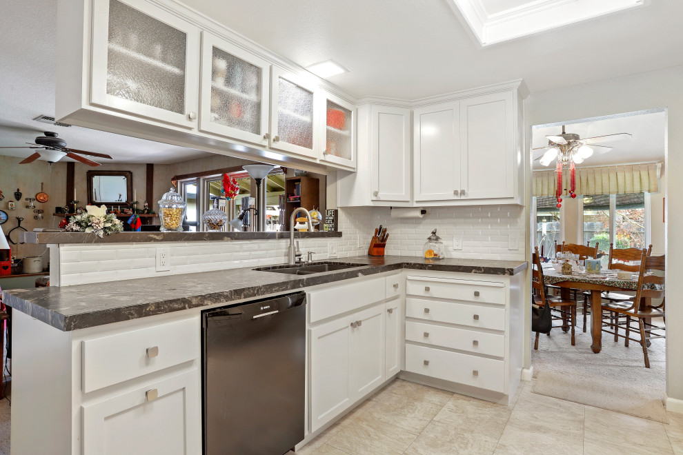 This is an example of a modern galley eat-in kitchen in Sacramento with a double-bowl sink, white cabinets, granite benchtops, white splashback, ceramic splashback, stainless steel appliances, no island, beige floor and grey benchtop.