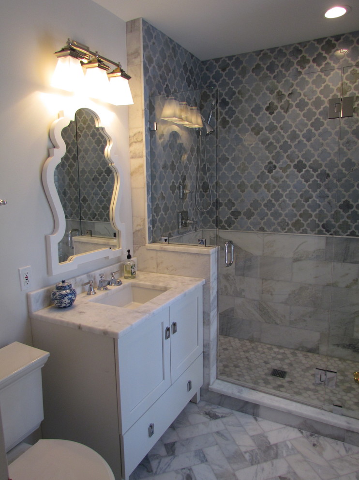 This is an example of a mid-sized transitional 3/4 bathroom in St Louis with a one-piece toilet, grey walls, marble floors, white floor, recessed-panel cabinets, white cabinets, an alcove shower, marble, an undermount sink, marble benchtops, a hinged shower door and white benchtops.