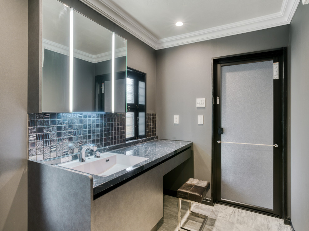 東京都下にあるトラディショナルスタイルのおしゃれなトイレ・洗面所 (グレーのキャビネット、グレーのタイル、モザイクタイル、グレーの壁、大理石の床、アンダーカウンター洗面器、人工大理石カウンター、白い床、グレーの洗面カウンター) の写真