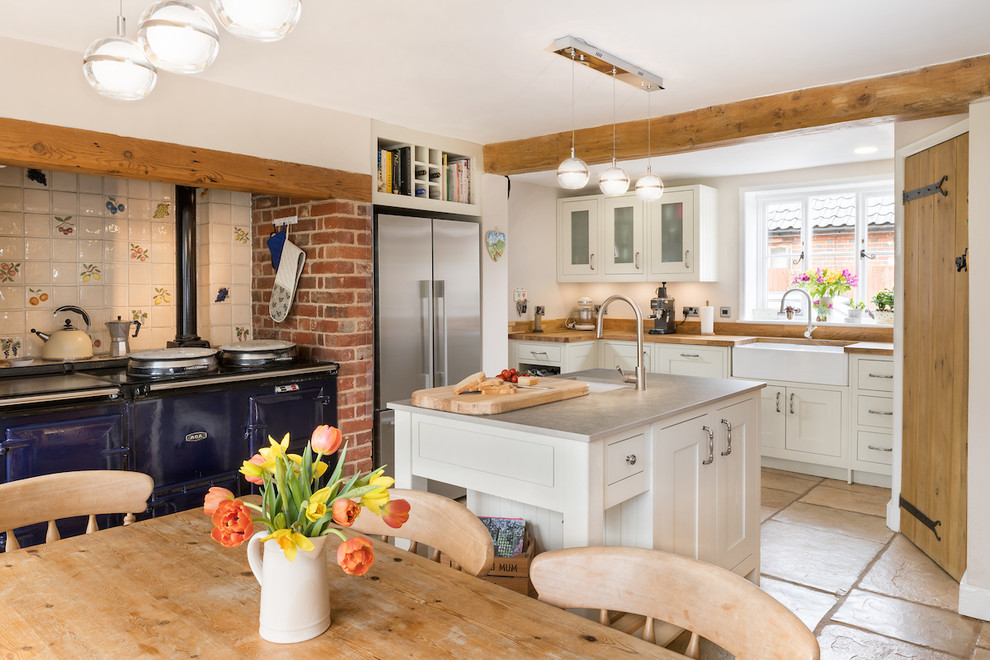 Inspiration for a country l-shaped eat-in kitchen in Other with a farmhouse sink, shaker cabinets, white cabinets, wood benchtops, white splashback, coloured appliances, with island, beige floor and brown benchtop.