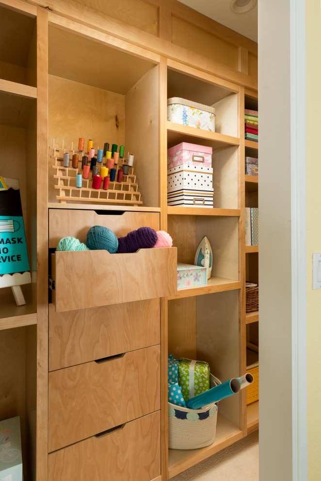This is an example of a mid-sized gender-neutral walk-in wardrobe in Seattle with flat-panel cabinets, light wood cabinets, carpet and white floor.