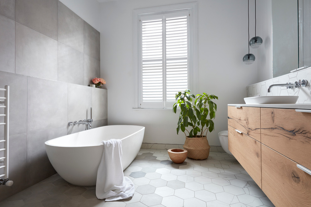 Inspiration for a large contemporary master bathroom in Melbourne with flat-panel cabinets, light wood cabinets, a freestanding tub, an open shower, gray tile, white tile, mosaic tile, white walls, mosaic tile floors, a vessel sink and solid surface benchtops.