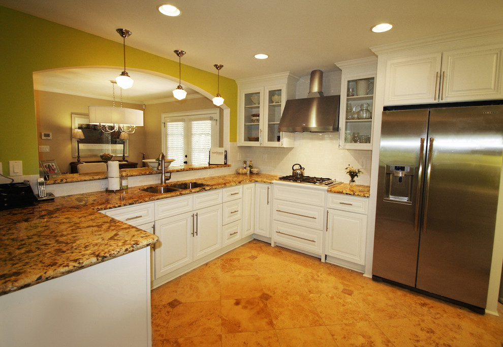 マイアミの中サイズのトランジショナルスタイルのおしゃれなキッチン (ダブルシンク、落し込みパネル扉のキャビネット、白いキャビネット、御影石カウンター、白いキッチンパネル、シルバーの調理設備、サブウェイタイルのキッチンパネル、セラミックタイルの床、茶色い床) の写真