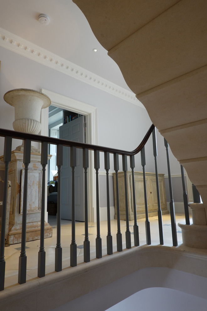 Traditional limestone curved staircase in Other with limestone risers and wood railing.