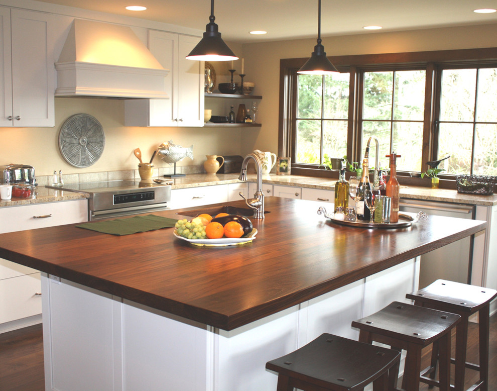 Example of a large transitional l-shaped medium tone wood floor and brown floor open concept kitchen design in Seattle with an undermount sink, shaker cabinets, white cabinets, wood countertops, gray backsplash, ceramic backsplash, stainless steel appliances and an island