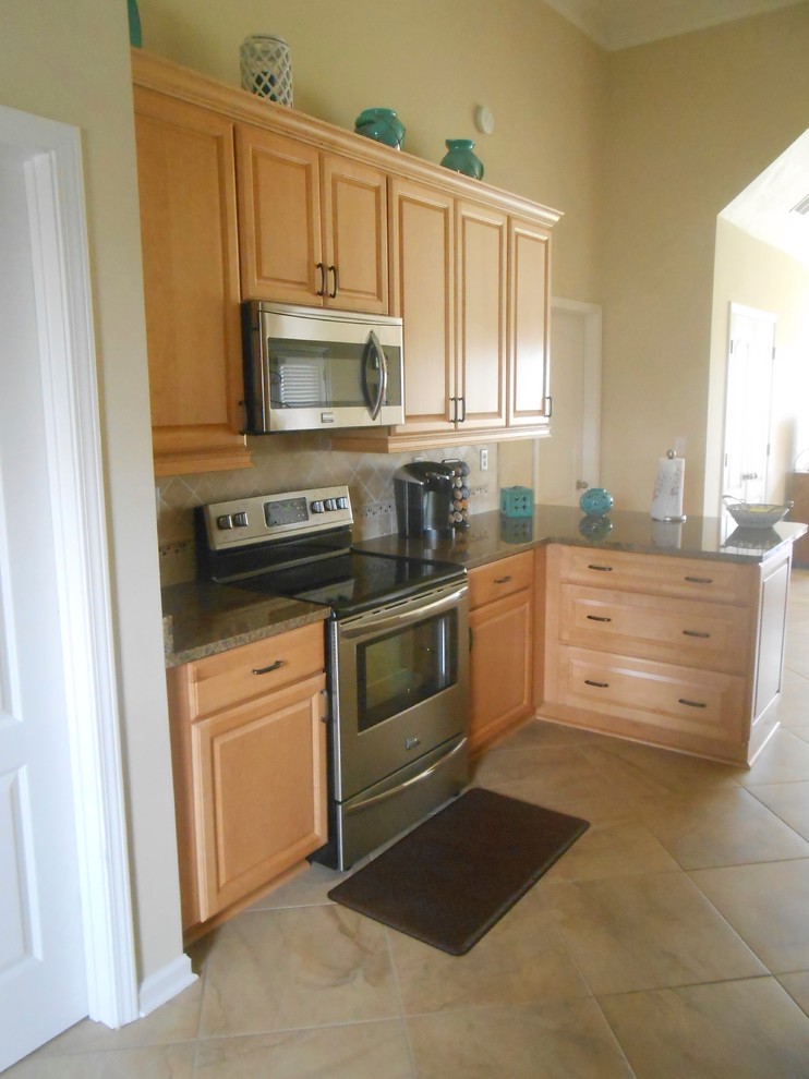 Example of a mid-sized minimalist galley porcelain tile eat-in kitchen design in Nashville with an undermount sink, raised-panel cabinets, light wood cabinets, granite countertops, beige backsplash, stone tile backsplash, stainless steel appliances and a peninsula