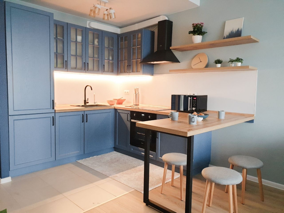 Small scandinavian u-shaped open plan kitchen in Moscow with an undermount sink, recessed-panel cabinets, blue cabinets, laminate benchtops, white splashback, black appliances, porcelain floors, a peninsula, beige floor and beige benchtop.