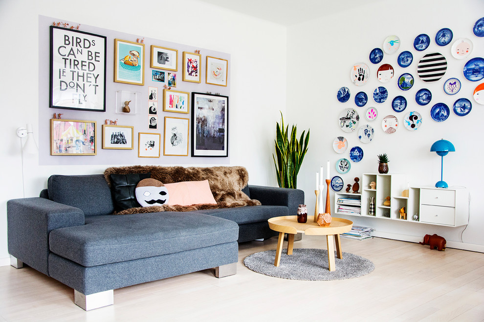 Photo of an eclectic living room with white walls, light hardwood floors and beige floor.