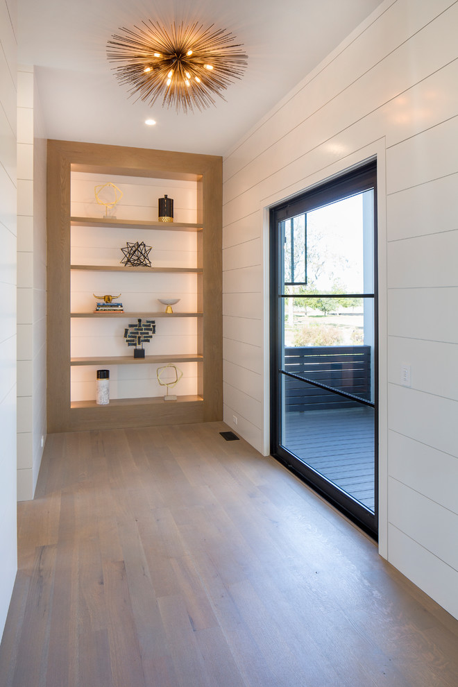 Inspiration for an expansive contemporary front door in Charleston with white walls, medium hardwood floors, a pivot front door, a metal front door and grey floor.