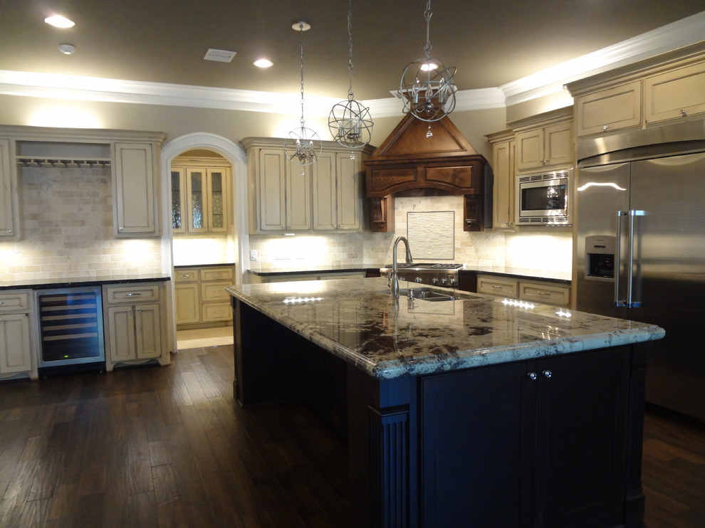 Design ideas for a traditional l-shaped open plan kitchen in Houston with a double-bowl sink, recessed-panel cabinets, distressed cabinets, granite benchtops, beige splashback, stone tile splashback, stainless steel appliances, medium hardwood floors and with island.