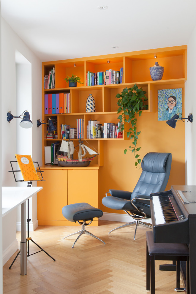 Small contemporary home office in London with orange walls, light hardwood floors and a freestanding desk.