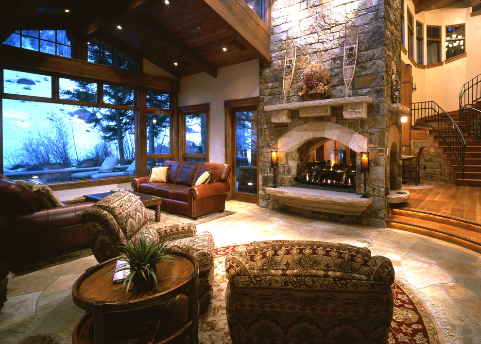 This is an example of a large arts and crafts formal open concept living room in Denver with beige walls, travertine floors, a two-sided fireplace and a stone fireplace surround.