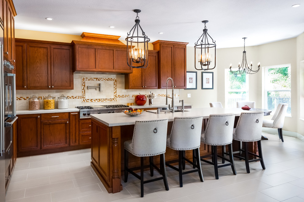 Large traditional l-shaped eat-in kitchen in San Francisco with an undermount sink, recessed-panel cabinets, medium wood cabinets, quartz benchtops, beige splashback, stone tile splashback, stainless steel appliances, porcelain floors, with island, beige floor and beige benchtop.