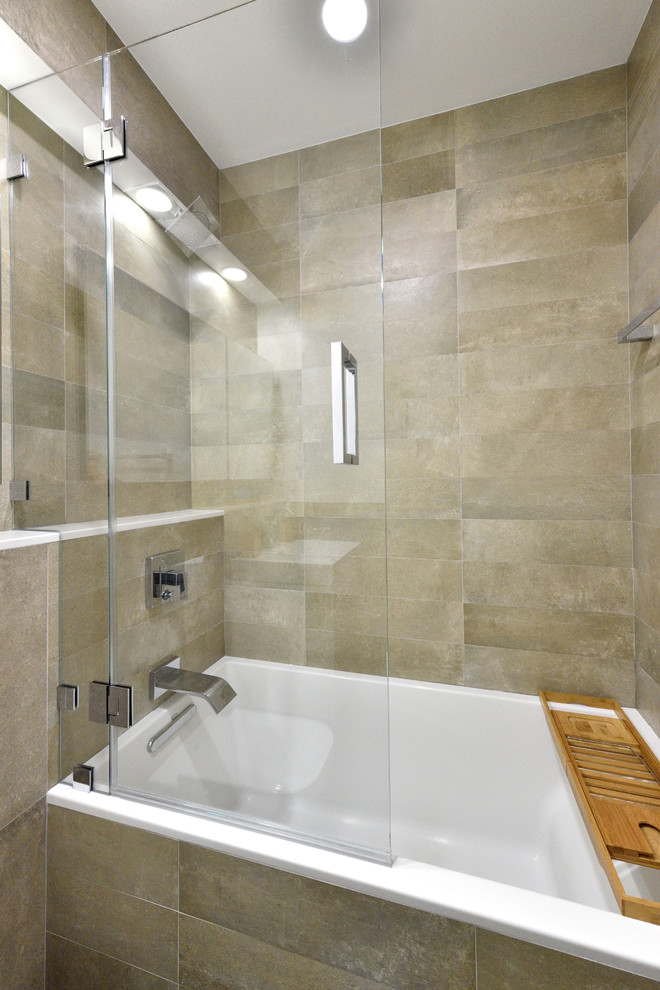 This is an example of a small contemporary master bathroom in New York with flat-panel cabinets, white cabinets, a drop-in tub, a shower/bathtub combo, a wall-mount toilet, gray tile, ceramic tile, multi-coloured walls, ceramic floors and a wall-mount sink.