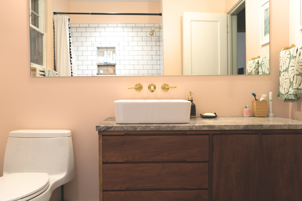 Small transitional master bathroom in Richmond with an alcove tub, a shower/bathtub combo, a one-piece toilet, white tile, ceramic tile, pink walls, ceramic floors, a vessel sink, black floor, a shower curtain, grey benchtops, furniture-like cabinets, medium wood cabinets and marble benchtops.
