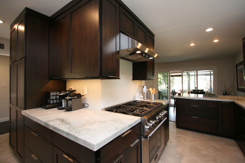 Example of a mid-sized transitional l-shaped porcelain tile kitchen design in Orange County with a double-bowl sink, recessed-panel cabinets, dark wood cabinets, quartzite countertops, white backsplash, glass tile backsplash, stainless steel appliances and no island