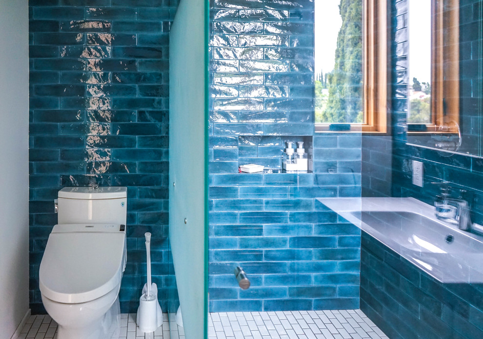 ロサンゼルスにある中くらいなトランジショナルスタイルのおしゃれなバスルーム (浴槽なし) (インセット扉のキャビネット、白いキャビネット、コーナー設置型シャワー、青いタイル、セラミックタイル、青い壁、白い床、開き戸のシャワー、磁器タイルの床、一体型シンク、分離型トイレ、白い洗面カウンター) の写真