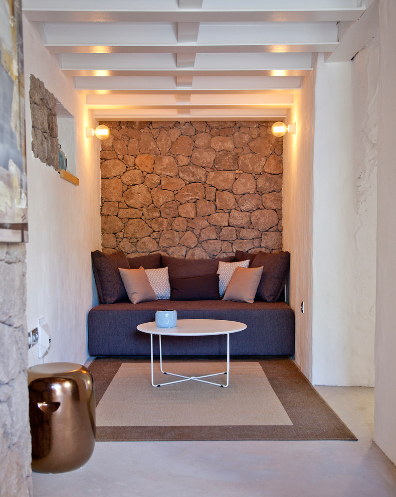 Modelo de sala de estar abierta mediterránea pequeña sin chimenea y televisor con paredes blancas y suelo de cemento