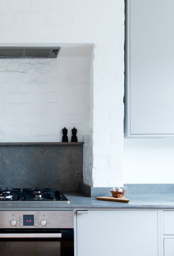 Inspiration for a small contemporary l-shaped eat-in kitchen in London with a double-bowl sink, flat-panel cabinets, grey cabinets, limestone benchtops, grey splashback, limestone splashback, stainless steel appliances, cork floors, no island and grey benchtop.