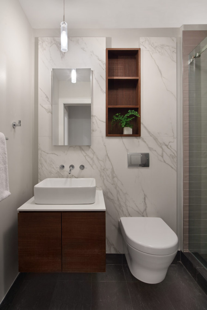 Design ideas for a small bathroom in New York with flat-panel cabinets, dark wood cabinets, an alcove tub, a shower/bathtub combo, a wall-mount toilet, white tile, marble, white walls, a vessel sink, solid surface benchtops, grey floor, an open shower, white benchtops, a niche, a single vanity, a floating vanity and porcelain floors.