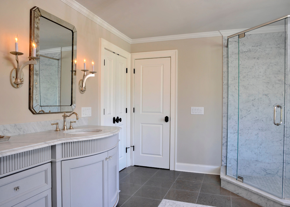 Photo of a large traditional master bathroom in Atlanta with recessed-panel cabinets, grey cabinets, a corner shower, a two-piece toilet, beige walls, ceramic floors, an undermount sink, marble benchtops, grey floor, a hinged shower door and multi-coloured benchtops.