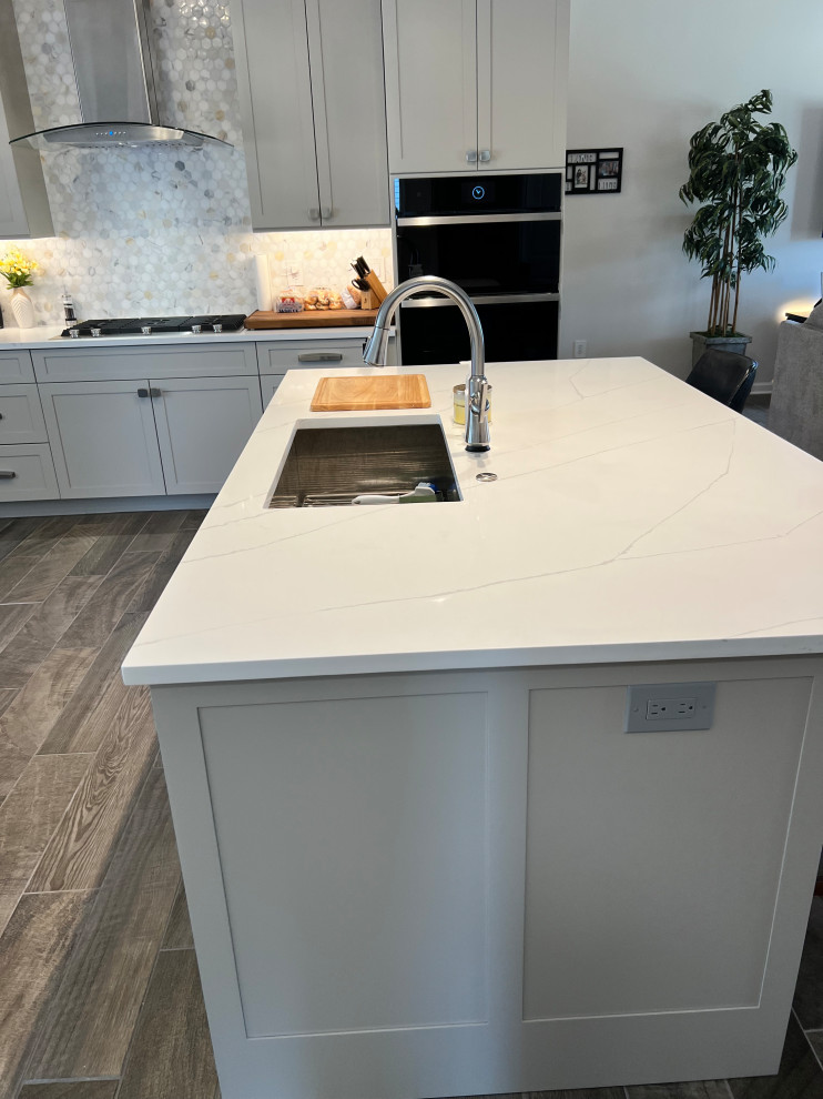 Large transitional u-shaped porcelain tile and brown floor eat-in kitchen photo in Austin with an undermount sink, shaker cabinets, gray cabinets, quartz countertops, white backsplash, marble backsplash, stainless steel appliances, an island and white countertops